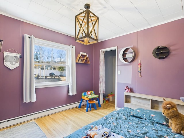 bedroom with baseboard heating, ornamental molding, and wood finished floors