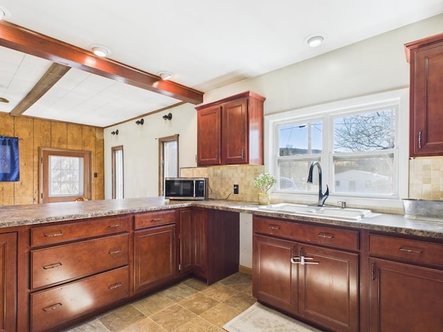 kitchen with stainless steel microwave, beamed ceiling, decorative backsplash, and a sink