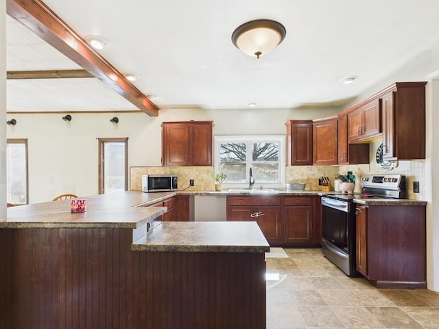 kitchen featuring a sink, appliances with stainless steel finishes, dark countertops, beamed ceiling, and backsplash