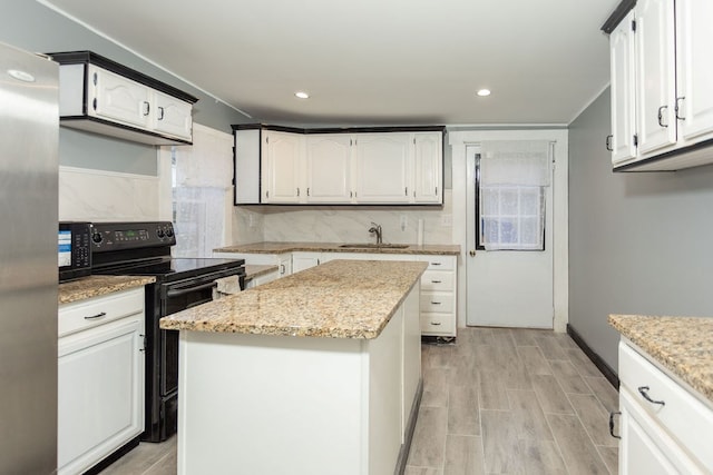 kitchen featuring a center island, black appliances, white cabinets, sink, and light hardwood / wood-style floors