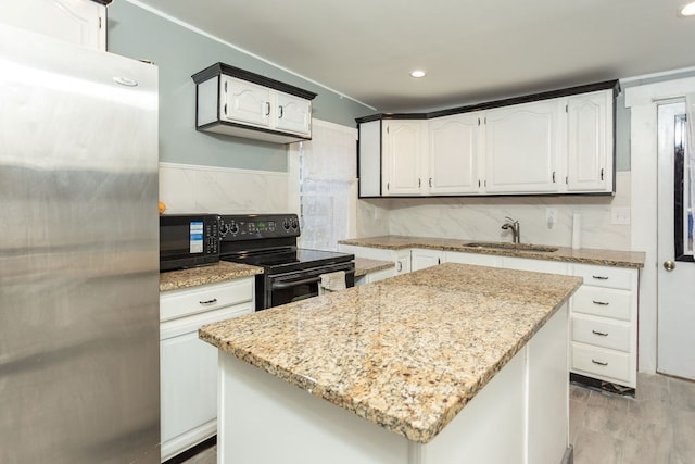 kitchen featuring a center island, sink, light stone counters, white cabinets, and black appliances