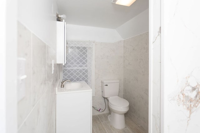 bathroom featuring vanity, toilet, and tile walls