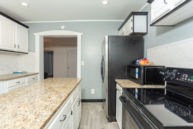 kitchen featuring light stone counters, backsplash, crown molding, white cabinets, and black appliances