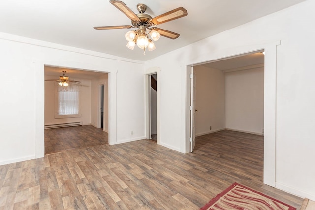 spare room with dark hardwood / wood-style floors, ceiling fan, and a baseboard heating unit