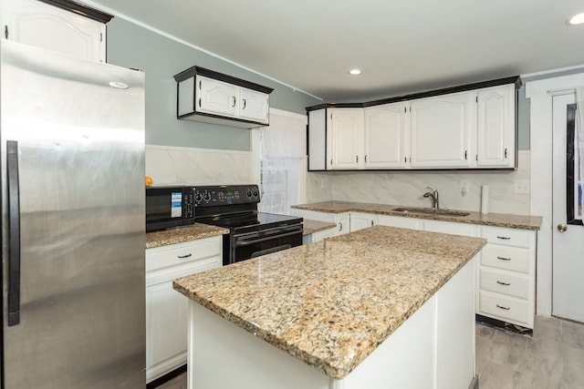 kitchen featuring black appliances, white cabinets, sink, a kitchen island, and light stone counters