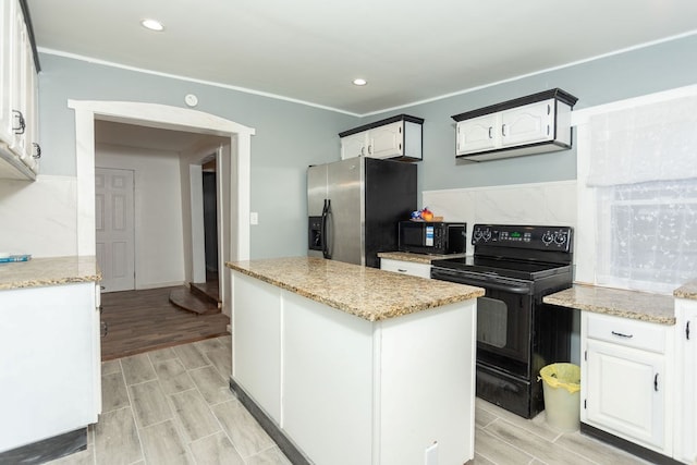 kitchen featuring black appliances, a center island, white cabinets, and light stone counters