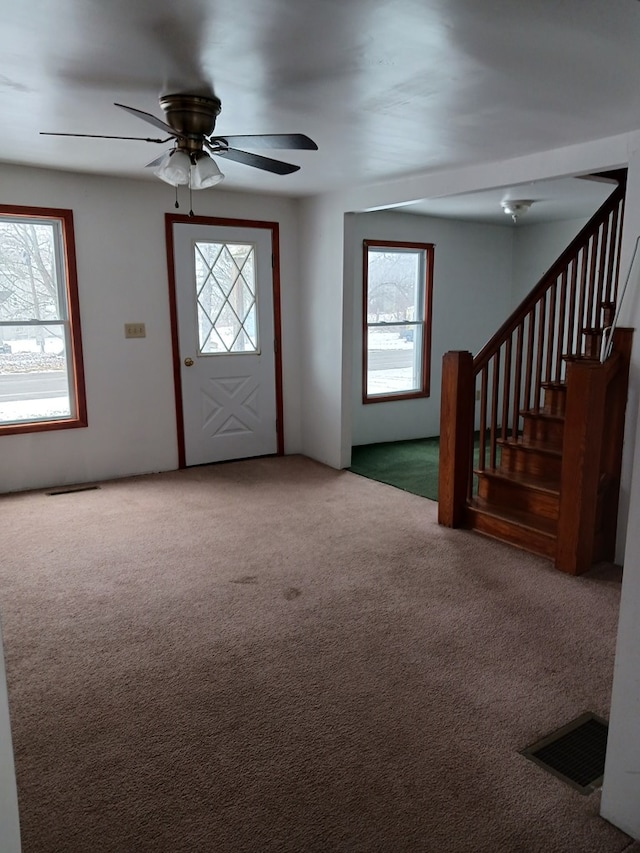 entrance foyer featuring carpet, a wealth of natural light, and ceiling fan