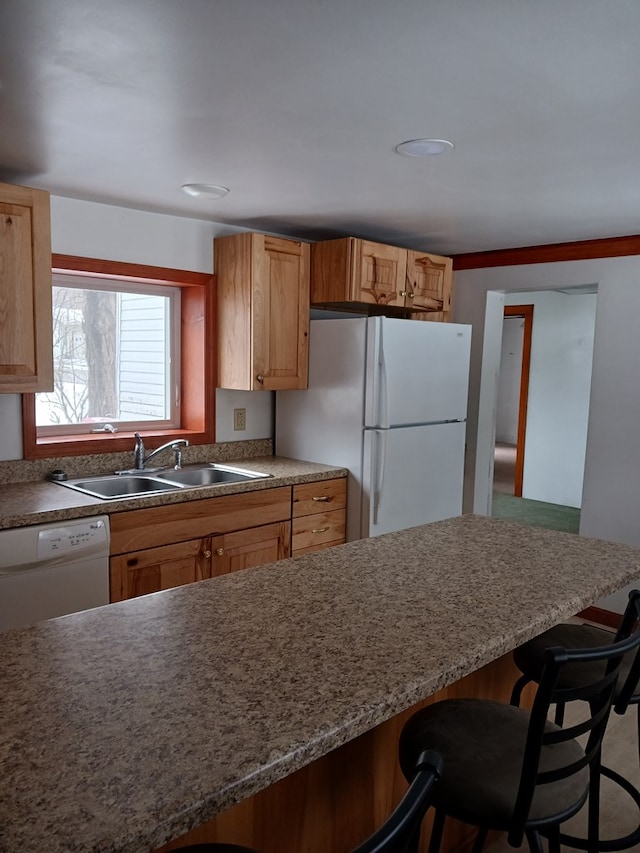 kitchen with sink, white appliances, and a breakfast bar