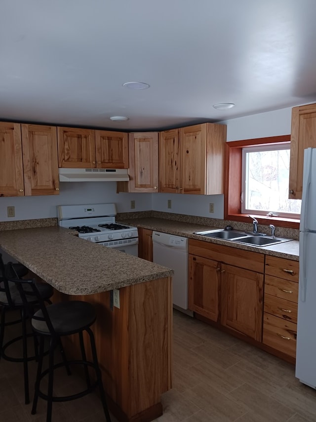 kitchen featuring a kitchen breakfast bar, sink, white appliances, and kitchen peninsula