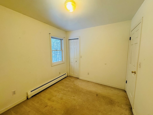 unfurnished bedroom featuring light colored carpet and a baseboard heating unit