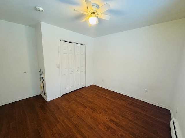 unfurnished bedroom with a baseboard radiator, dark wood-type flooring, a closet, and ceiling fan