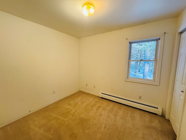 carpeted empty room featuring a baseboard heating unit