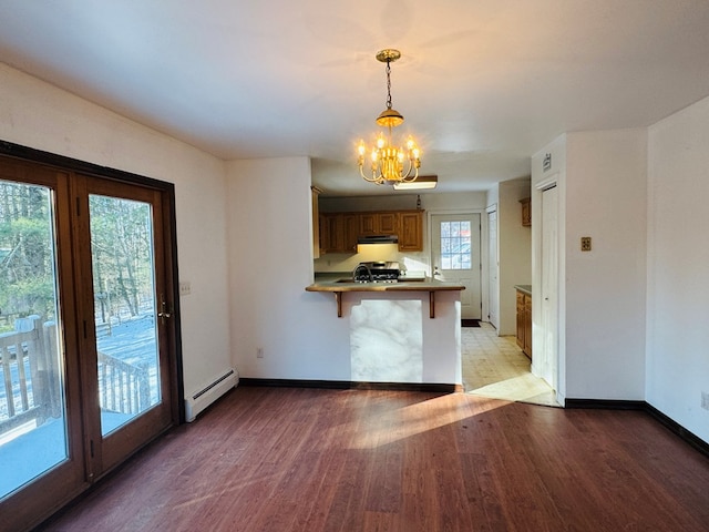 kitchen with a baseboard radiator, a kitchen bar, stainless steel range, kitchen peninsula, and hardwood / wood-style flooring