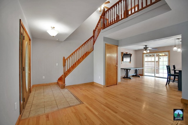 entrance foyer with ceiling fan with notable chandelier and light wood-type flooring