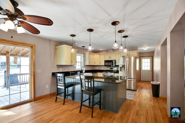 kitchen featuring kitchen peninsula, a healthy amount of sunlight, stainless steel appliances, and decorative light fixtures