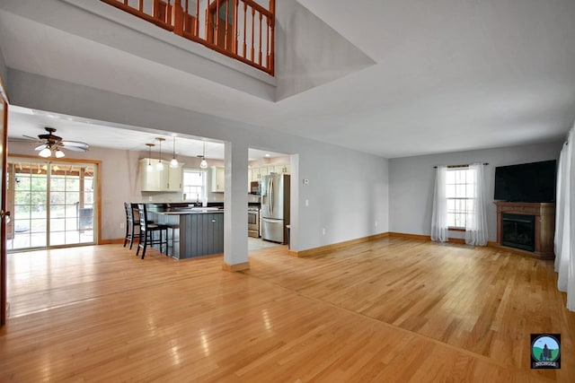 unfurnished living room featuring plenty of natural light, ceiling fan, and light wood-type flooring