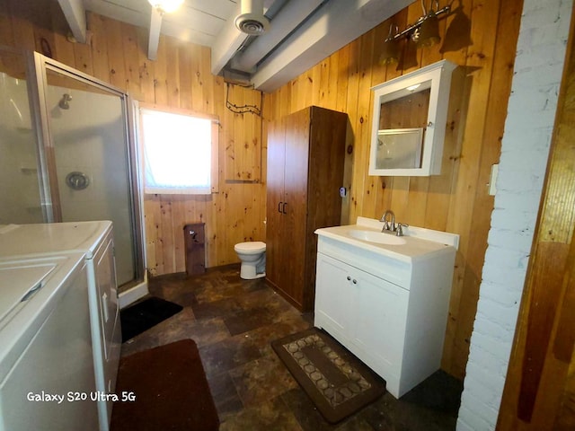 bathroom with vanity, wood walls, independent washer and dryer, and a shower with door