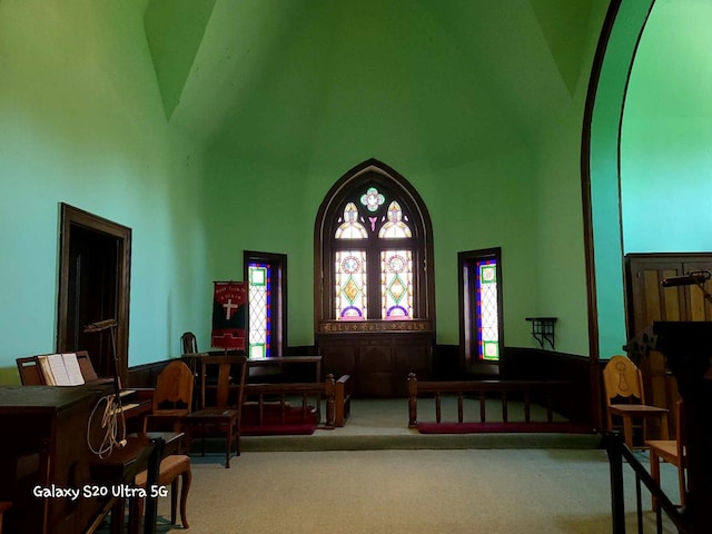 living area with carpet floors and high vaulted ceiling