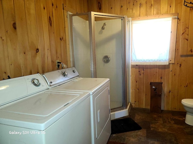 laundry area with wooden walls and washing machine and clothes dryer