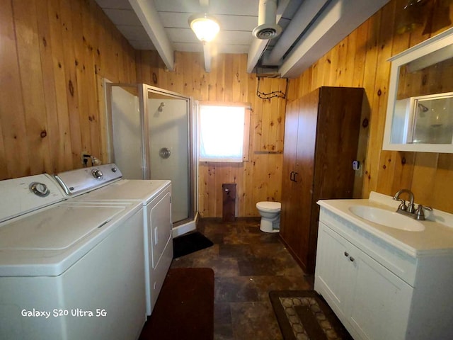 washroom with washer and dryer, wood walls, and sink