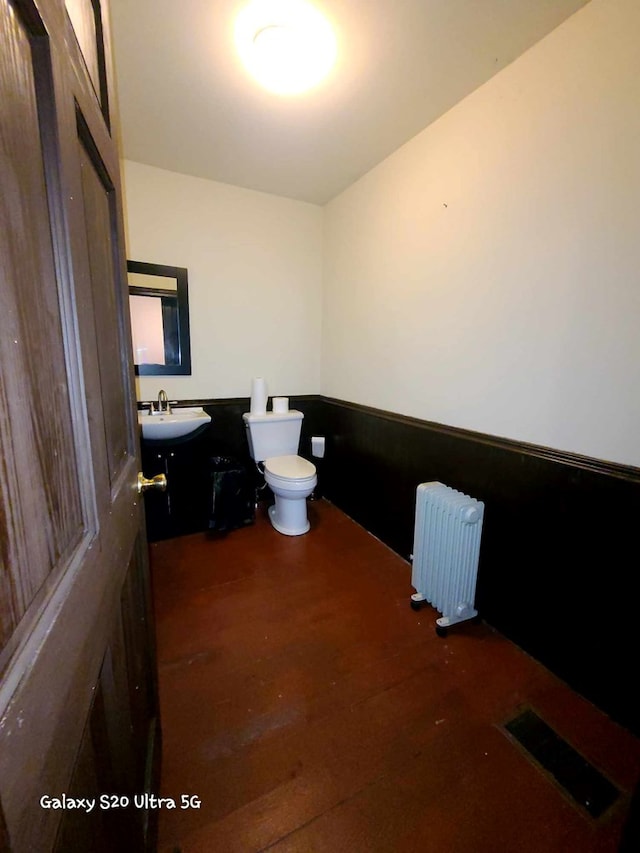 bathroom featuring toilet, wood-type flooring, sink, and radiator