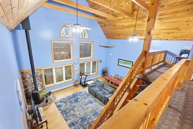 living room featuring a wood stove, high vaulted ceiling, wood-type flooring, beam ceiling, and wood ceiling