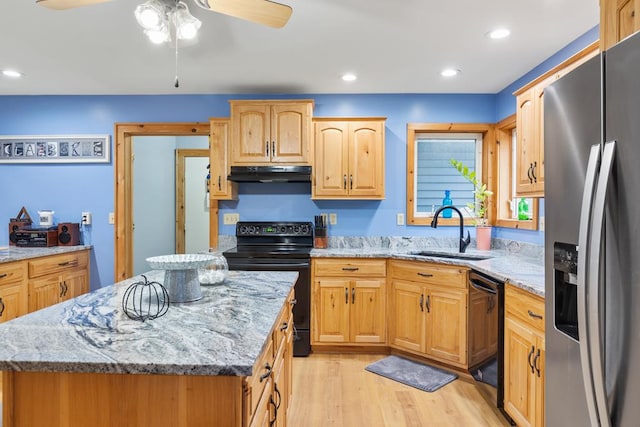 kitchen featuring sink, a kitchen island, black appliances, and light hardwood / wood-style flooring