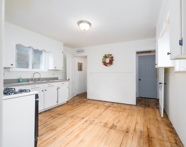 kitchen featuring white cabinets, light hardwood / wood-style flooring, white range with gas cooktop, and sink