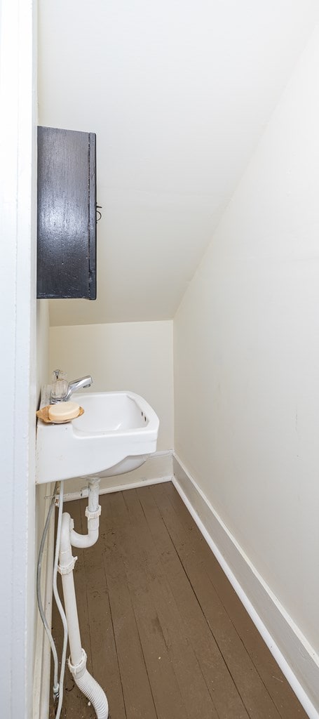 bathroom with sink, wood-type flooring, and vaulted ceiling