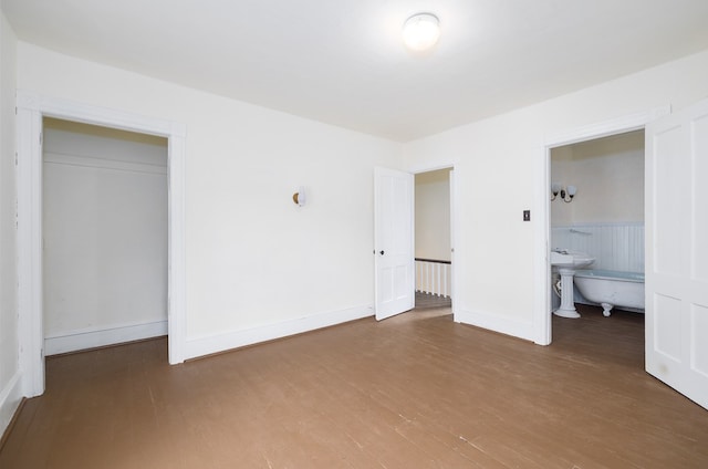 unfurnished bedroom featuring connected bathroom, a closet, and hardwood / wood-style flooring