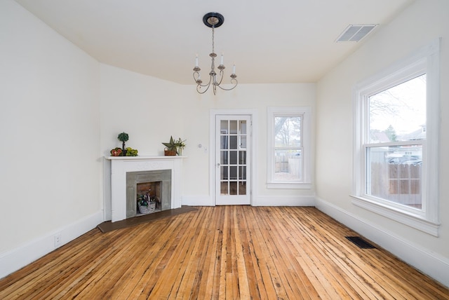 unfurnished living room with light wood-type flooring and an inviting chandelier