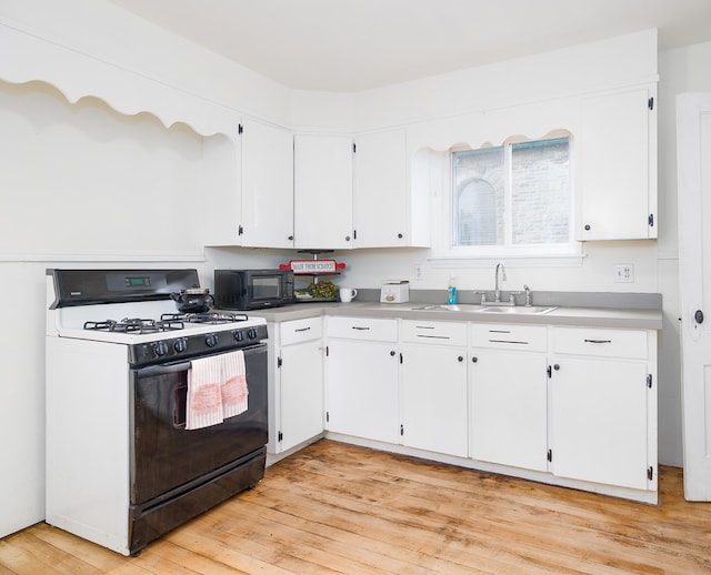 kitchen featuring white cabinets, light wood-type flooring, white gas range oven, and sink