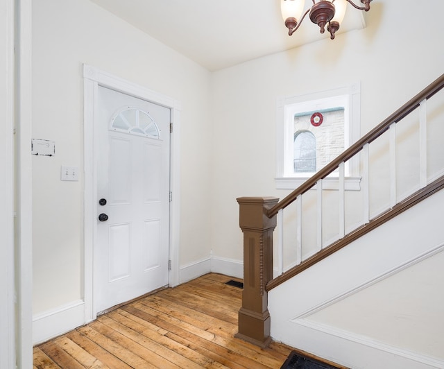 foyer entrance with light wood-type flooring and an inviting chandelier