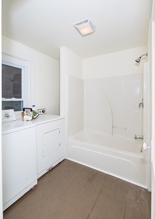 bathroom with hardwood / wood-style flooring, bathing tub / shower combination, and washer and clothes dryer