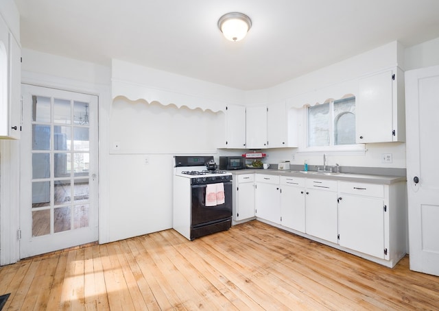 kitchen featuring white cabinets, light hardwood / wood-style flooring, gas range gas stove, and sink