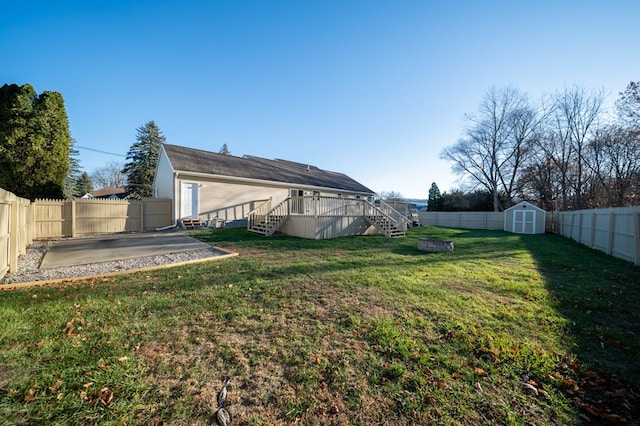 view of yard featuring a patio, a fenced backyard, an outdoor structure, a wooden deck, and a storage unit