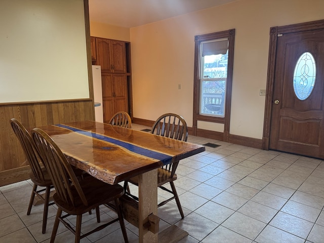 dining area with wooden walls and light tile patterned flooring