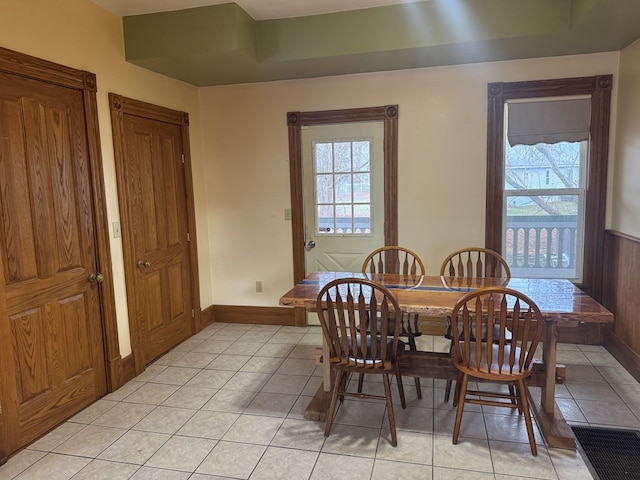 dining space with light tile patterned floors and wooden walls