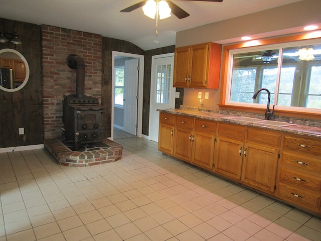 kitchen with a wood stove, a wealth of natural light, sink, and ceiling fan