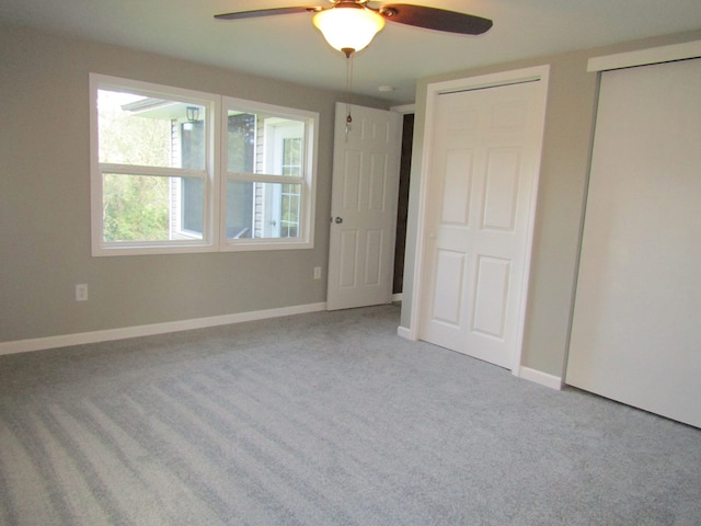 unfurnished bedroom featuring ceiling fan, light colored carpet, and two closets