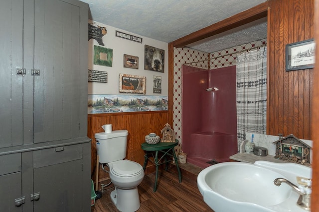 bathroom featuring hardwood / wood-style floors, a textured ceiling, curtained shower, toilet, and wood walls