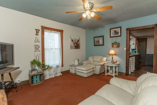 living room with ceiling fan, a textured ceiling, and dark colored carpet