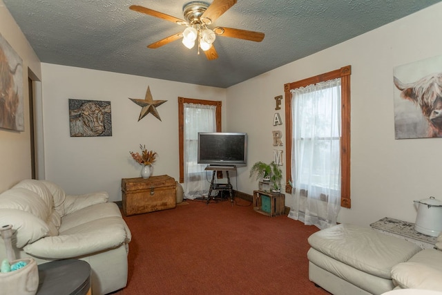 living room featuring ceiling fan, carpet flooring, and a textured ceiling