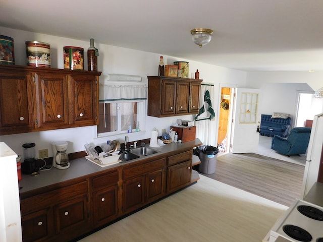 kitchen with dark brown cabinets, sink, light hardwood / wood-style floors, and range