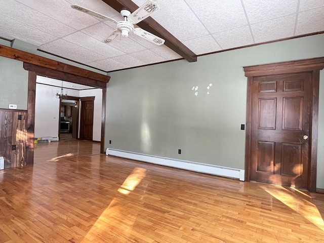 unfurnished room with a baseboard heating unit, ceiling fan, light hardwood / wood-style floors, ornamental molding, and beam ceiling