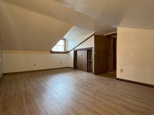 bonus room with hardwood / wood-style flooring and vaulted ceiling