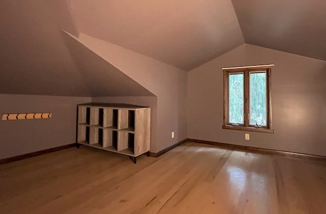 additional living space featuring light hardwood / wood-style flooring and lofted ceiling