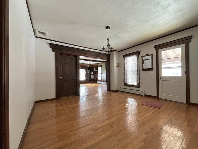 unfurnished dining area with baseboard heating, an inviting chandelier, a healthy amount of sunlight, and wood-type flooring