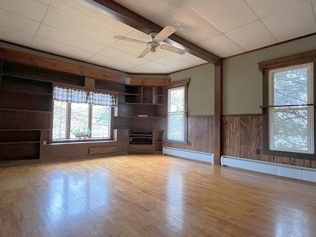 unfurnished living room with beamed ceiling, light wood-type flooring, ceiling fan, and a baseboard heating unit