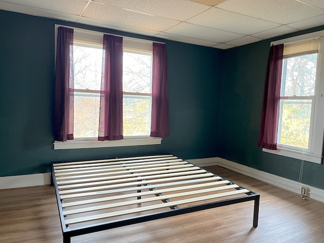 bedroom featuring a drop ceiling and wood-type flooring